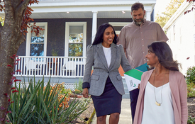 Man and woman walking with a REALTOR outside of home