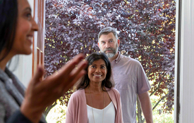 A middle-aged couple enters a home shown by a real estate agent